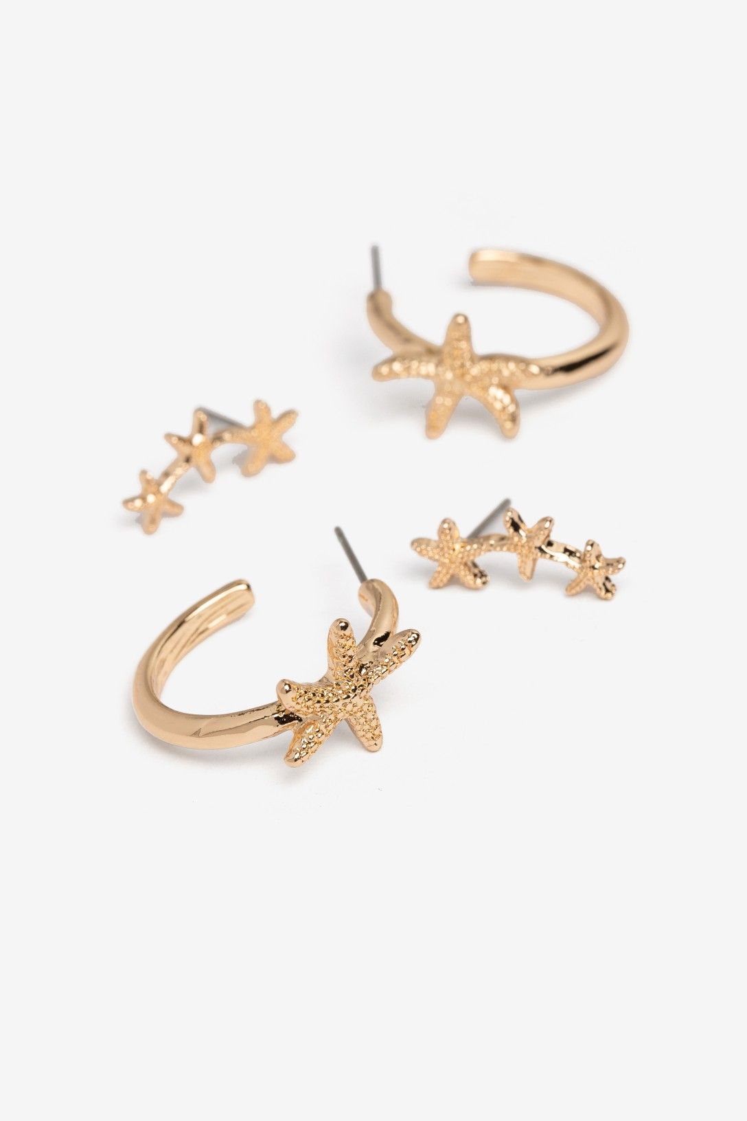 Pack de pendientes dorados Vilanova con diseño de estrellas de mar, compuesto por aros decorativos y pendientes trepadores.
