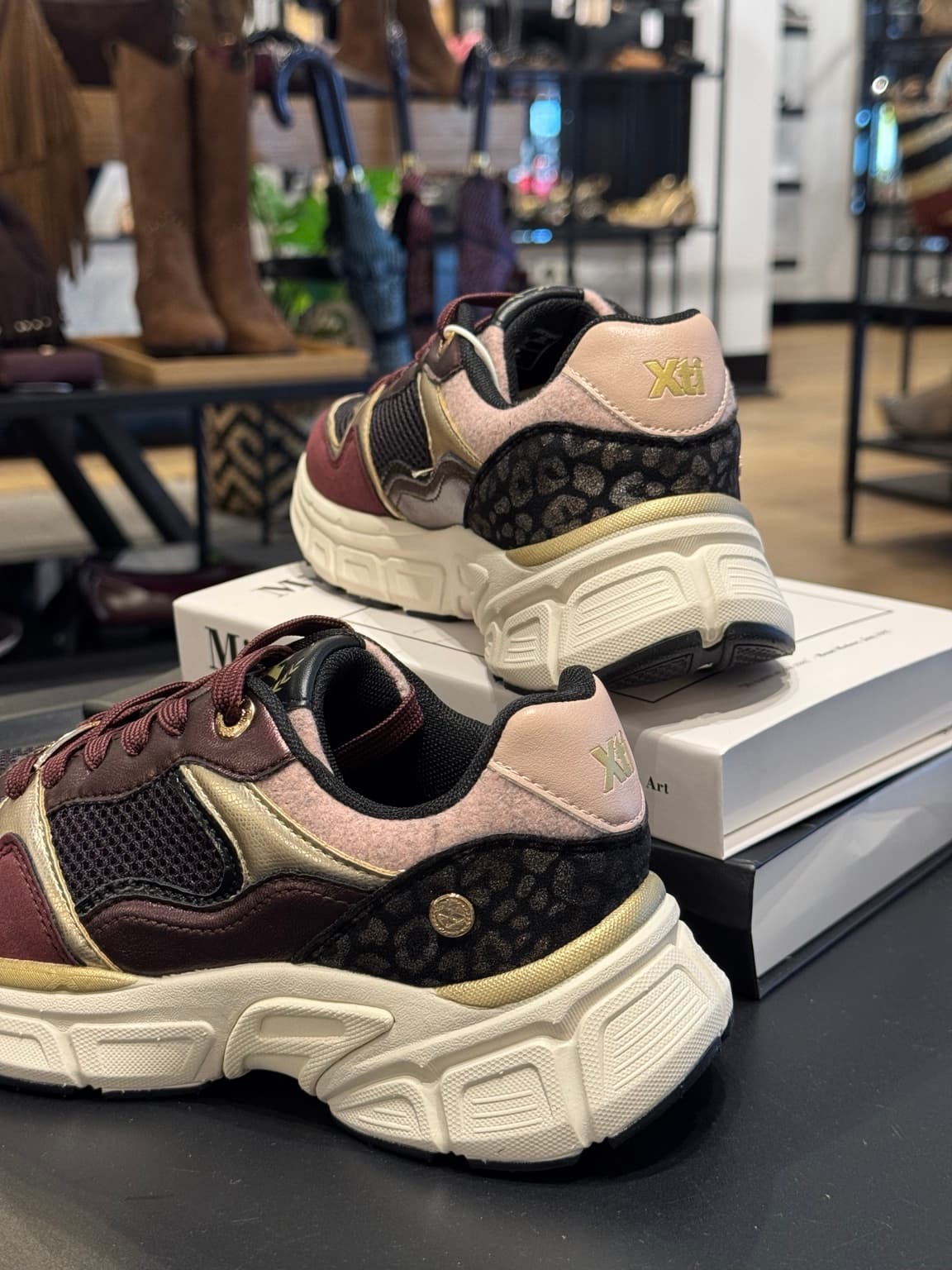 Deportiva Xti burdeos para mujer con detalles dorados, tejido transpirable, plantilla acolchada y suela gruesa ligera.